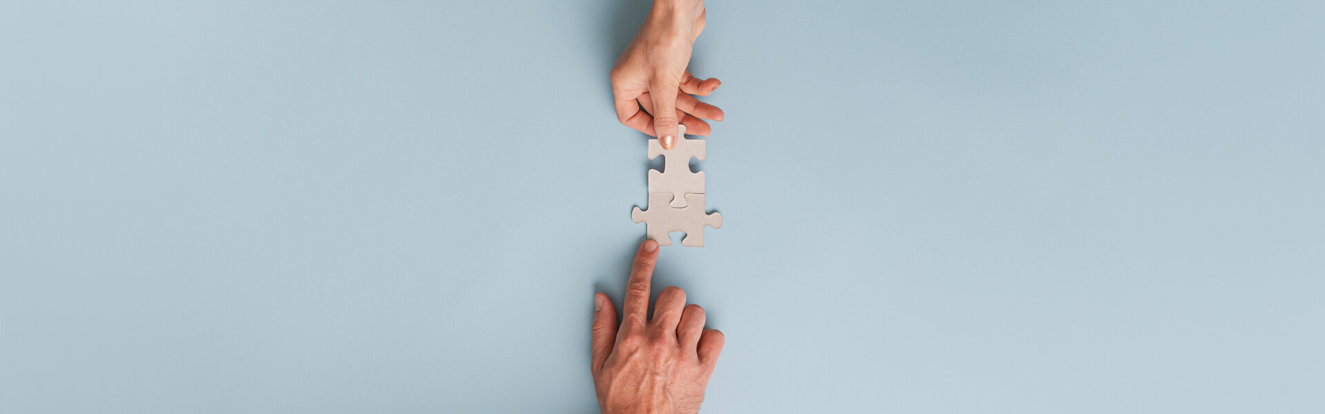 Zwei Hände, die passende Puzzleteile zusammenschieben