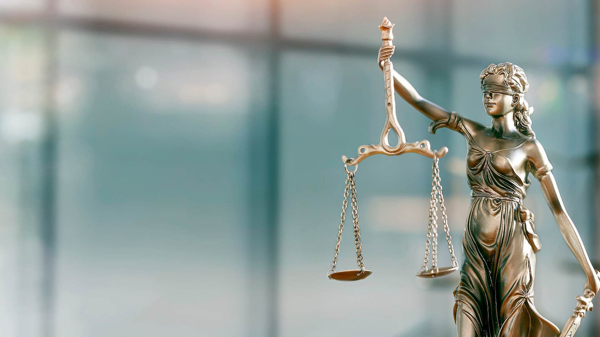 Justizia mit Waage und Schwert vor türkisfarbenem Hintergrund